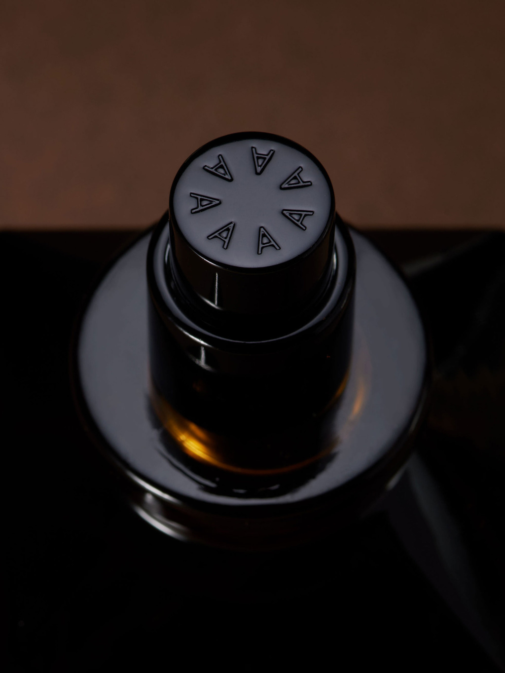 Top of perfume bottle with symbol made of A's