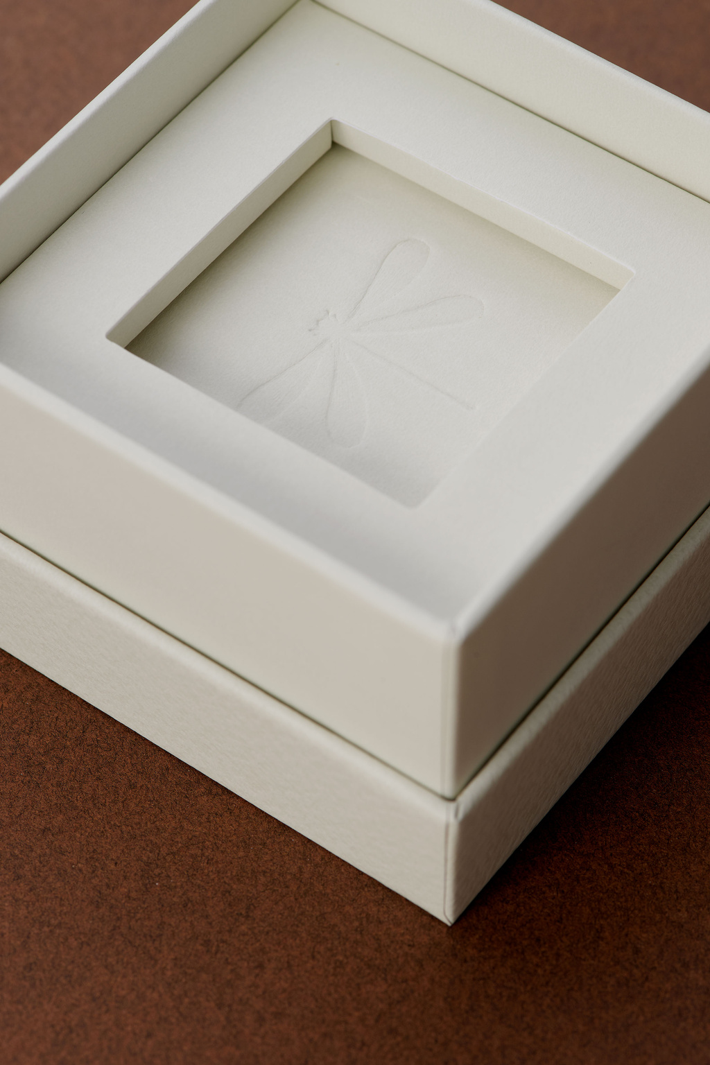 Close up on packaging with blind embossed dragonfly in the center