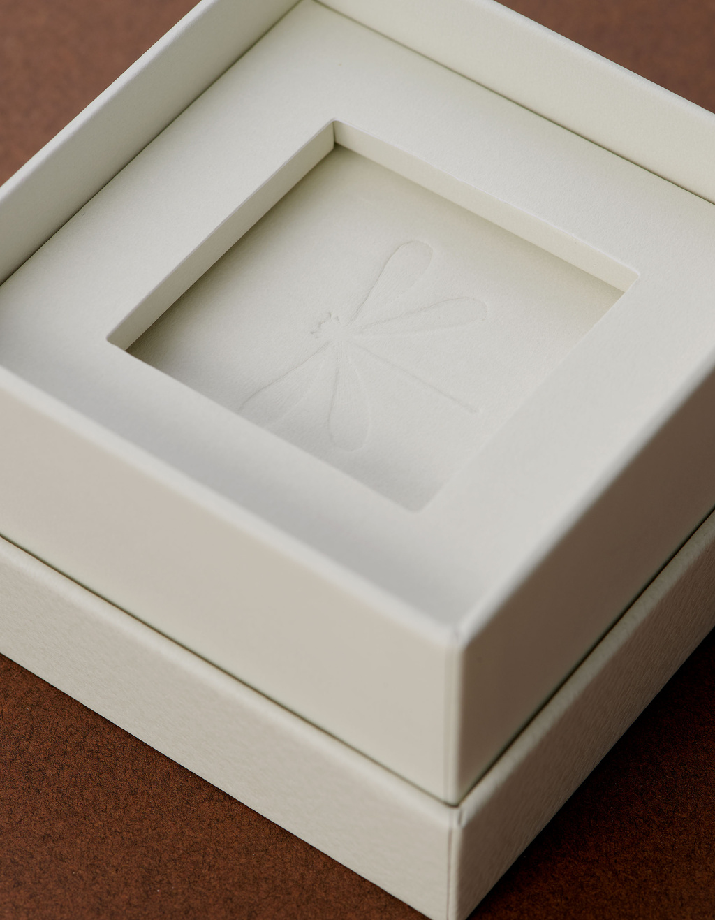 Close up on packaging with blind embossed dragonfly in the center
