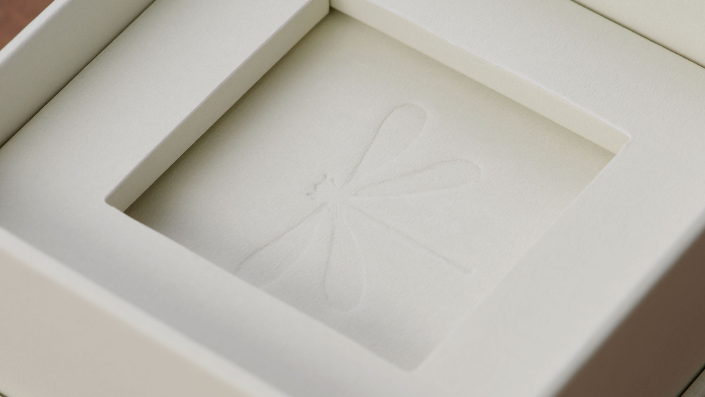 Close up on packaging with blind embossed dragonfly in the center