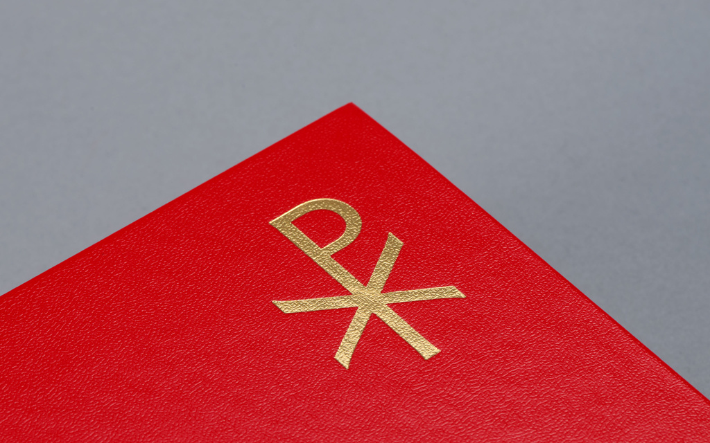A golden Christogram on red Bible