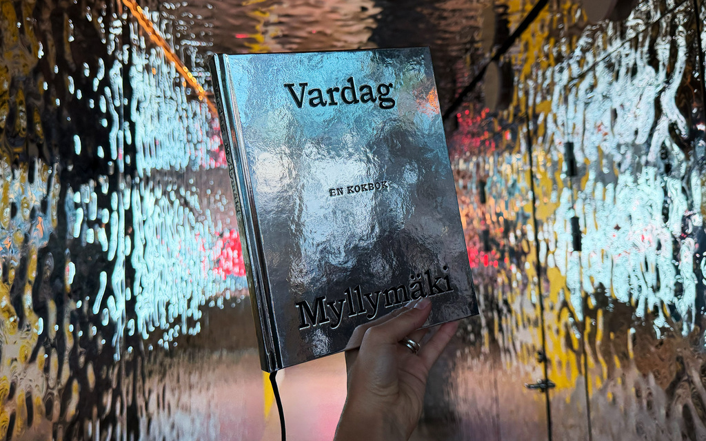 Book holds up inside a room of silver walls.